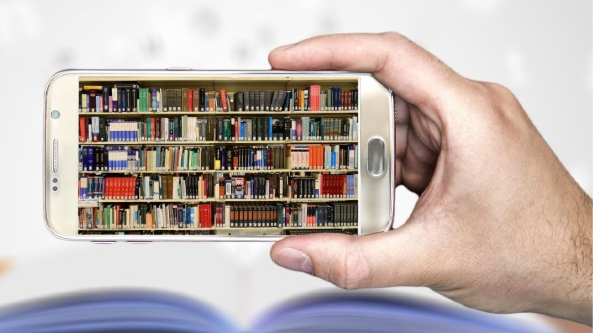 Smartphone displaying a bookshelf, held above an open book.