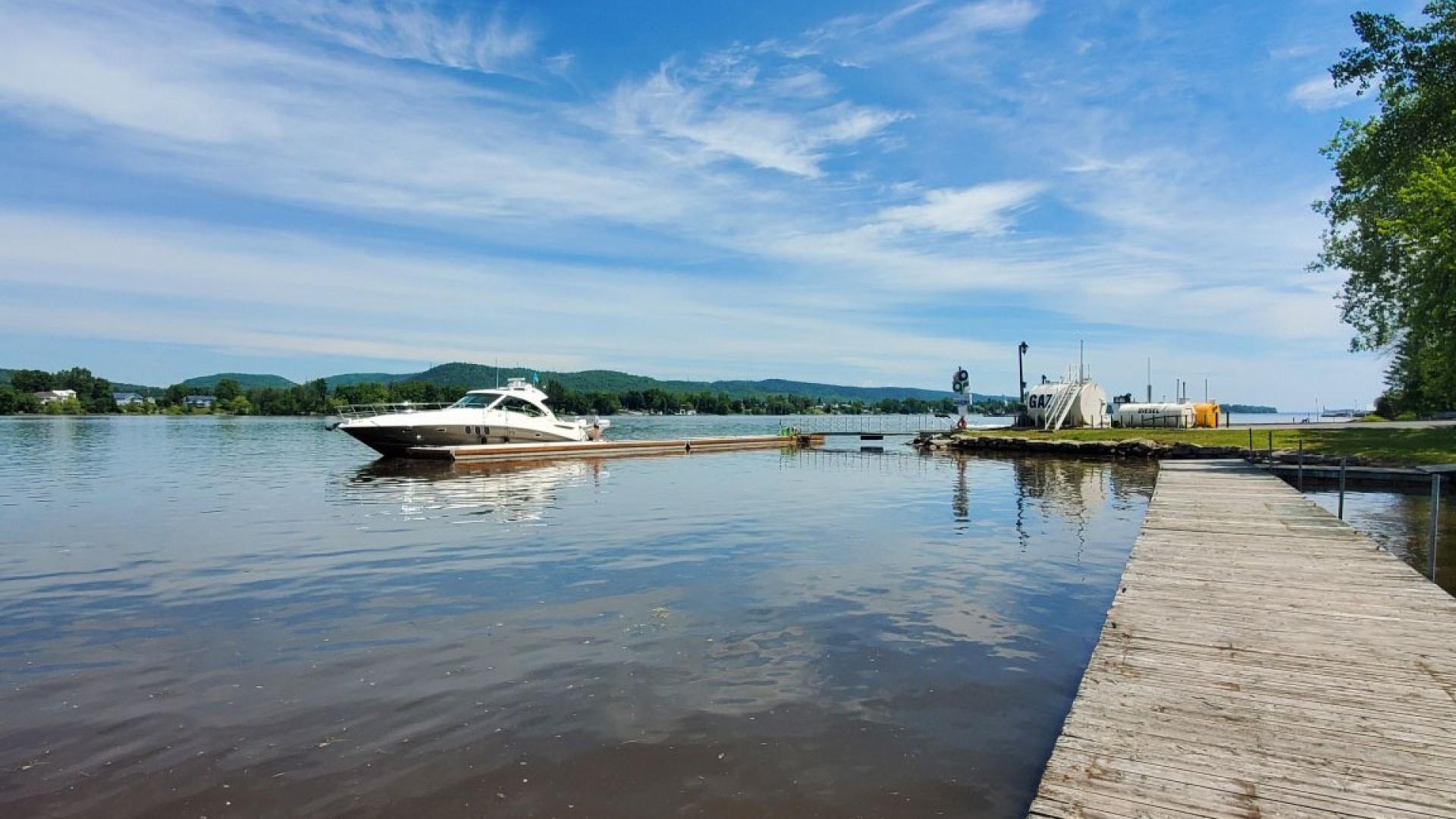 Docked boat on calm lake under a blue sky with scattered clouds.
