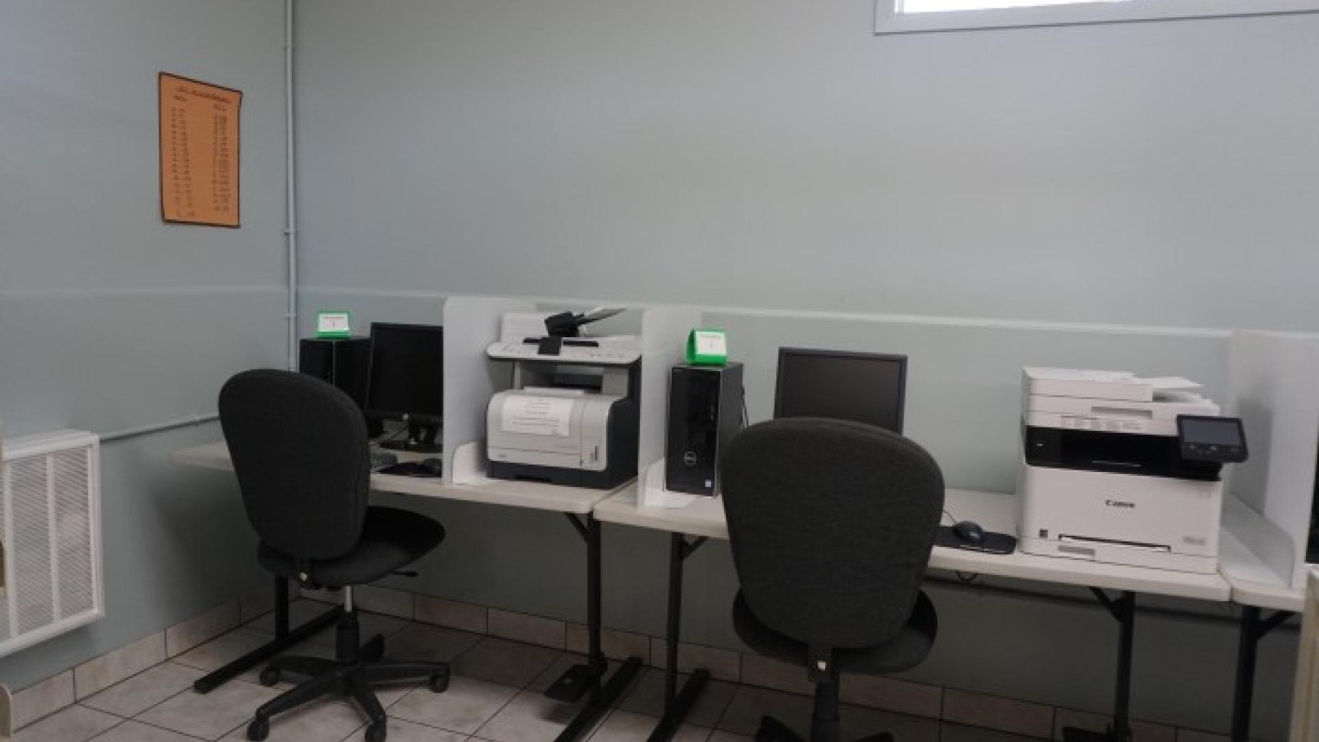Computer lab with two desks, monitors, and desktop printers.