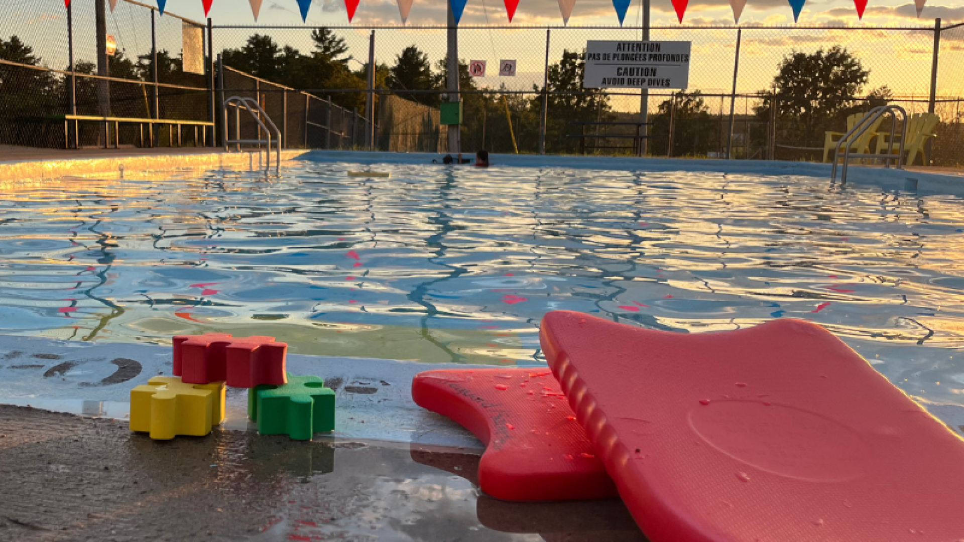 Couché de soleil sur la piscine avec jeux de piscine flottants en avant plan