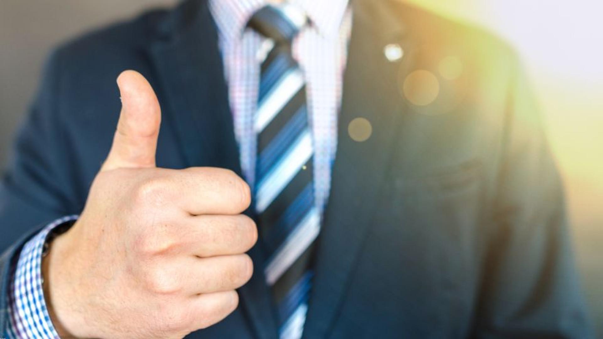Close-up of a person wearing a suit giving a thumbs up
