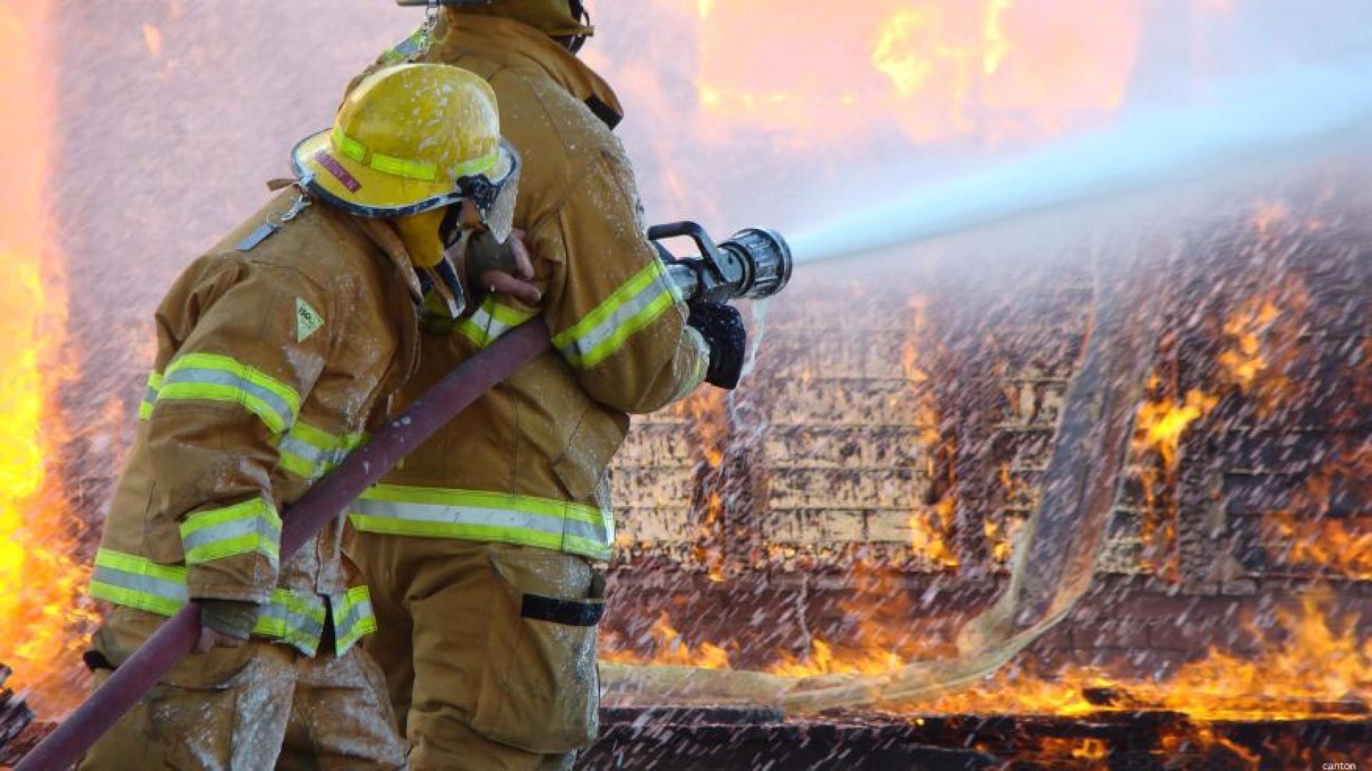 Two firefighters putting down a house fire