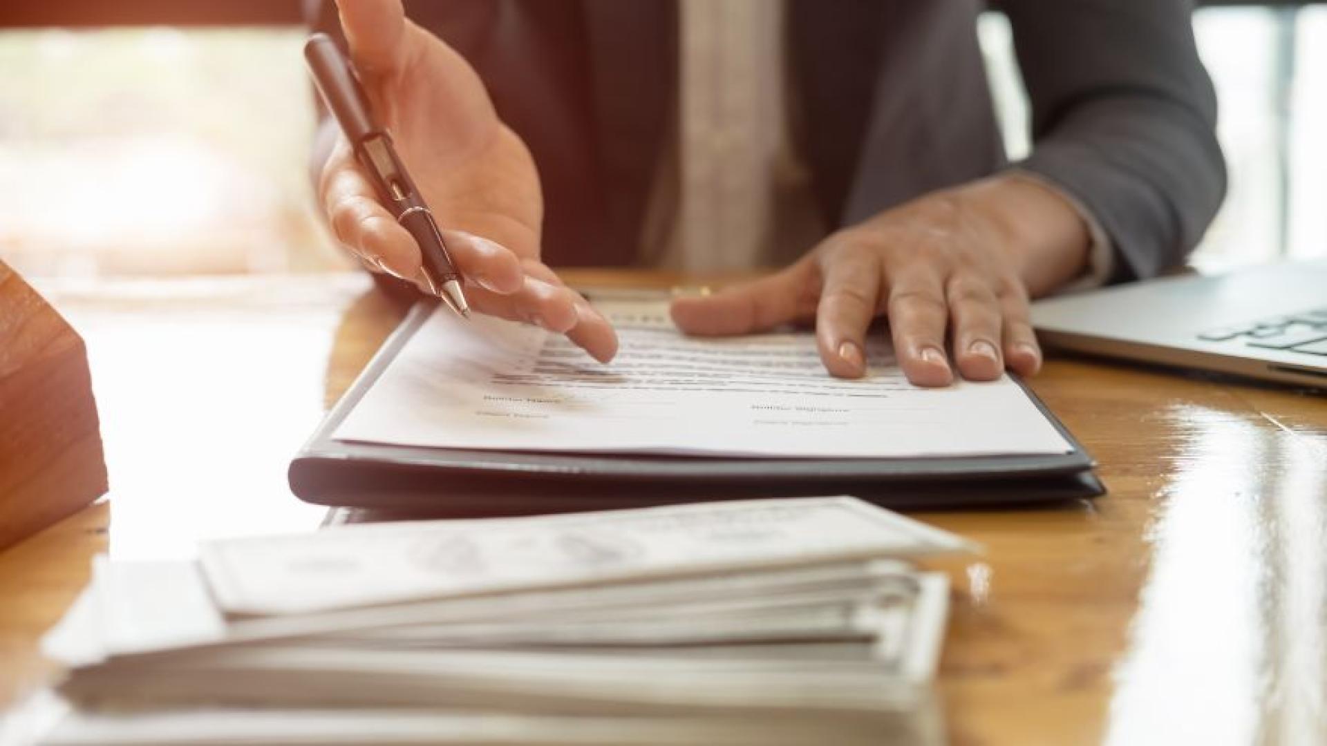 close up of someone holding a pen on top of documents
