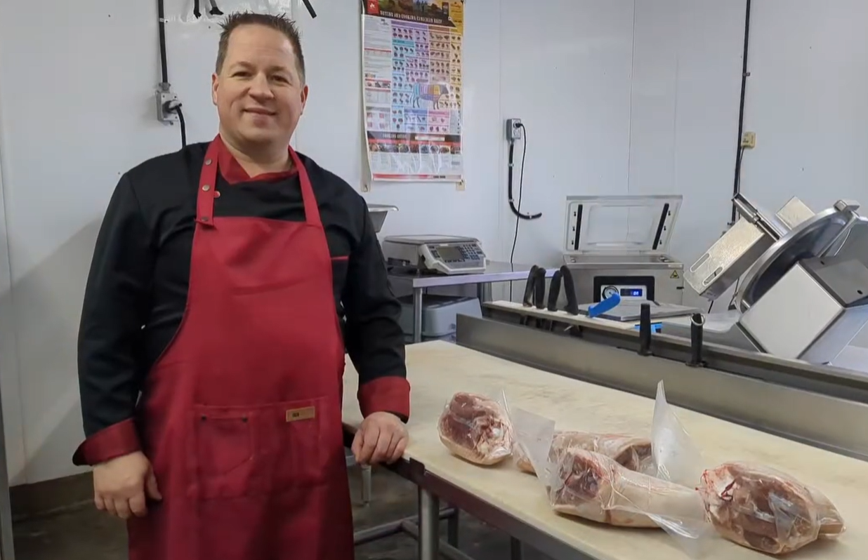 OwnerBenoit Bonneau standing at a counter in the shop with cuts of meat on the table 
