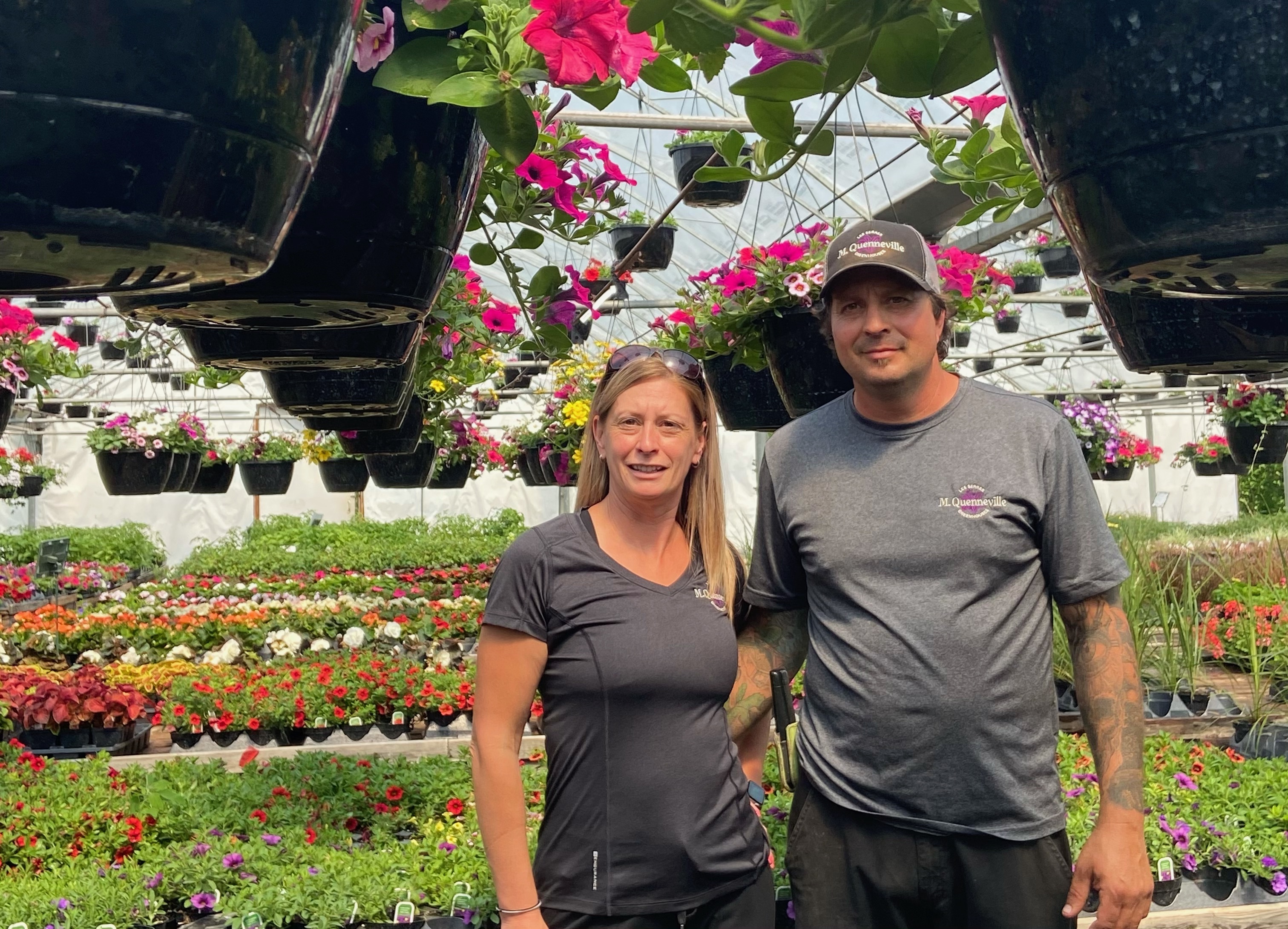 Owners of M.Quenneville Greenhouses in front of isles of flowers
