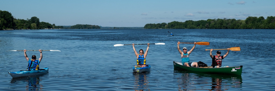 3 persons on kayaks in the water with their paddles and arms in the air