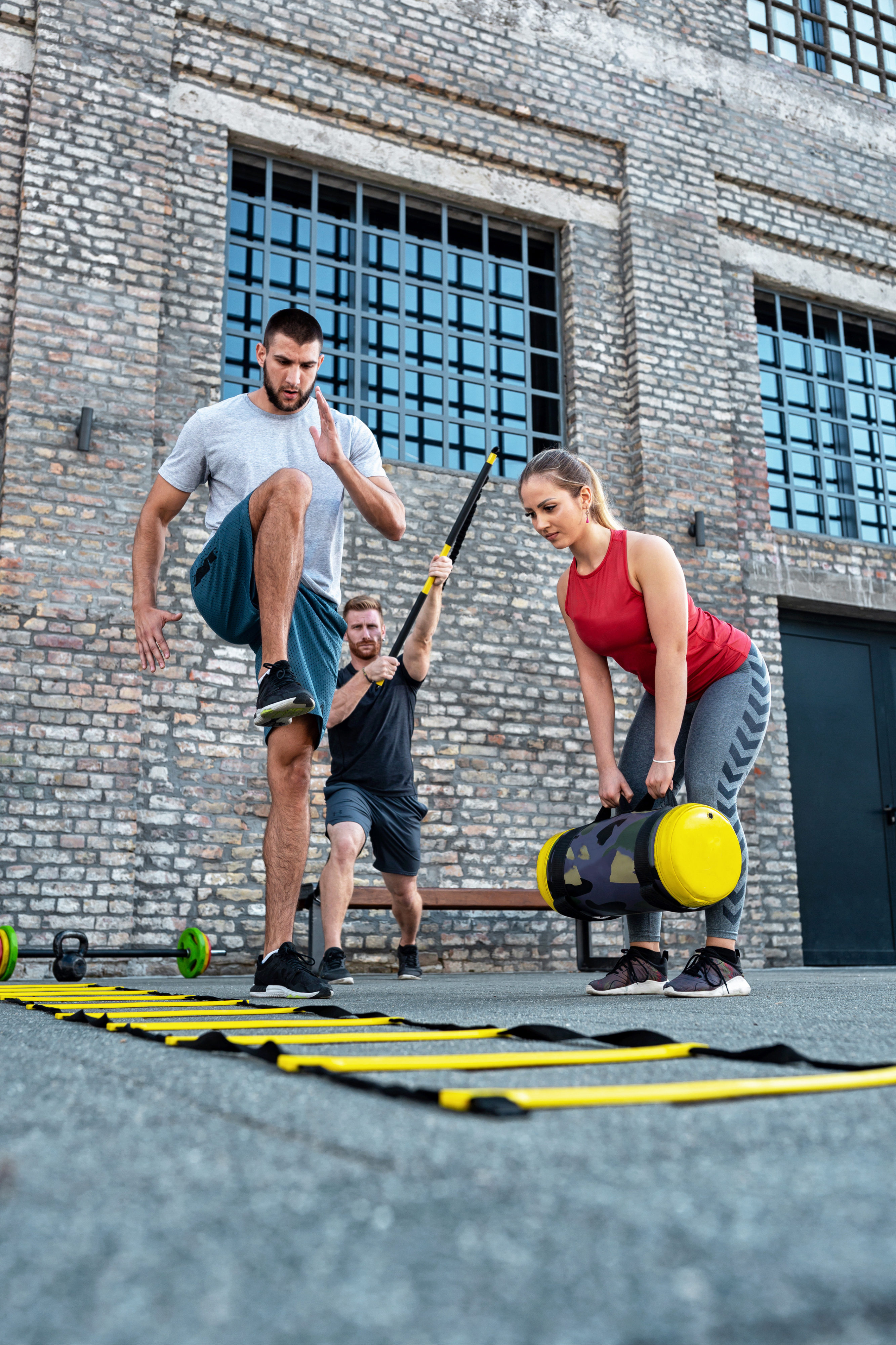 Two people working out, one on an agility ladder and one with weights