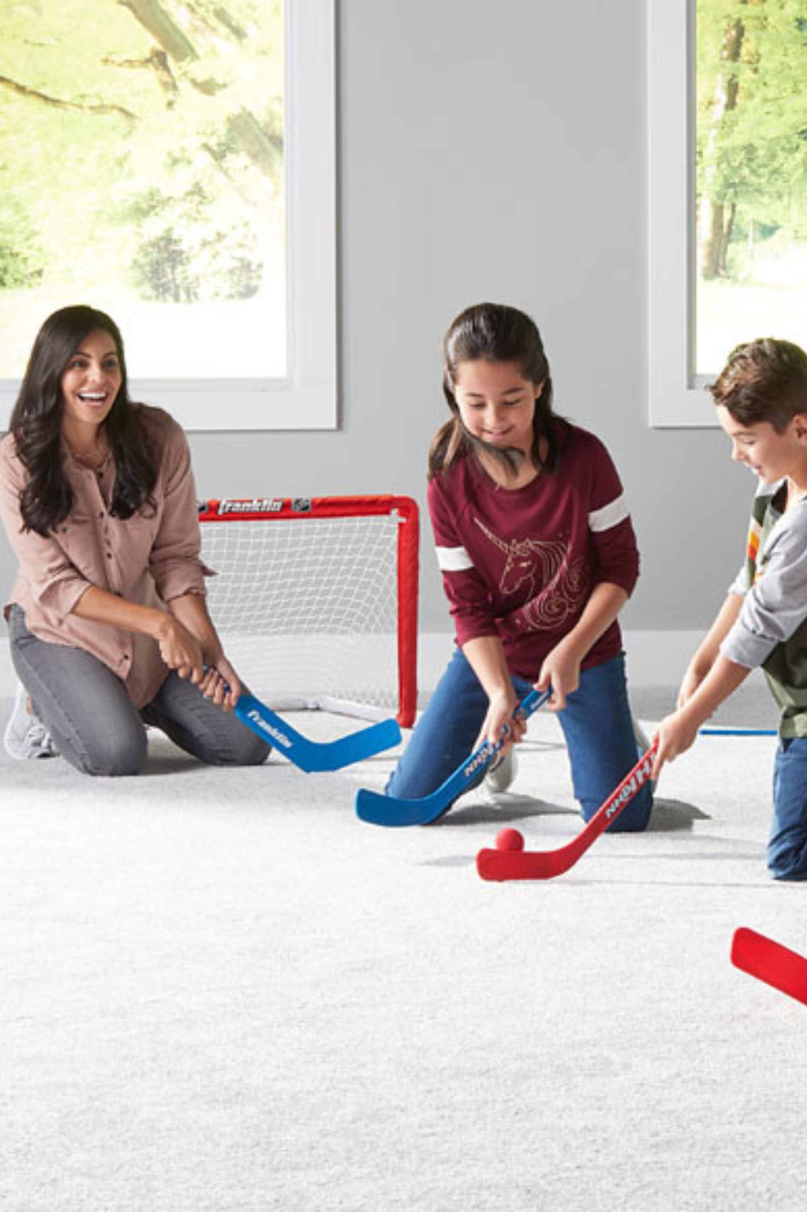 Un frère et une soeur qui jouent au hockey dans le salon avec leurs parents qui les regardent
