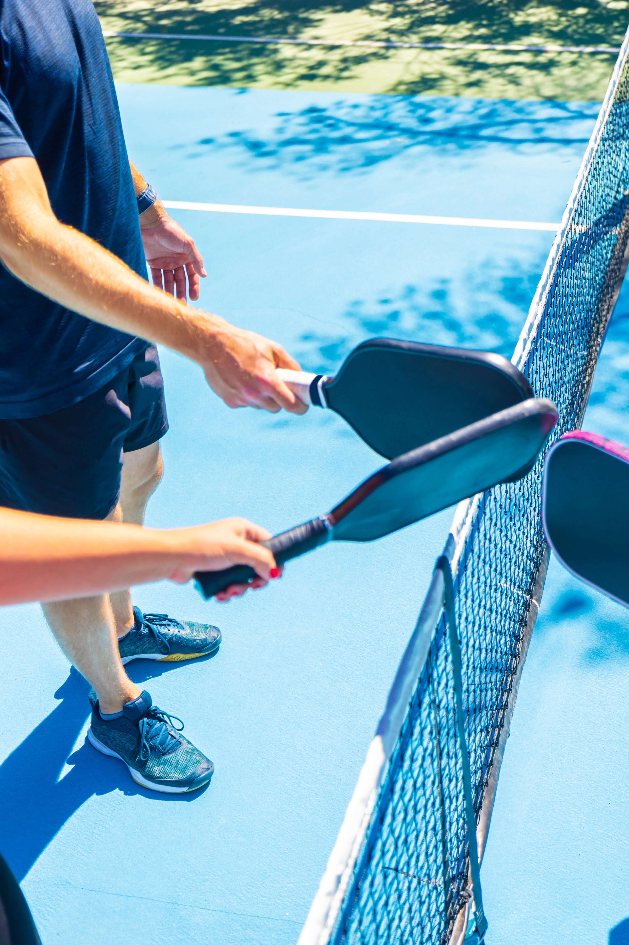 4 people on a pickleball field with the racquets together.