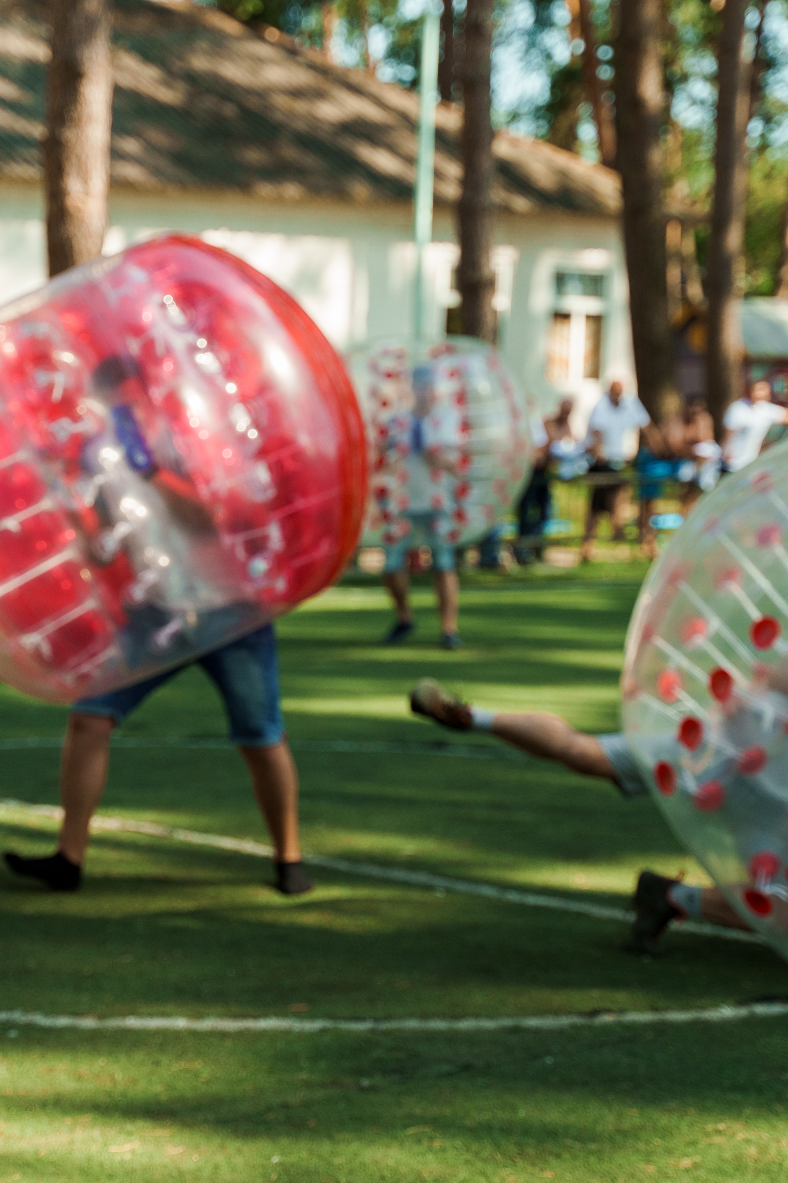 3 people with bubble soccer equipment outside