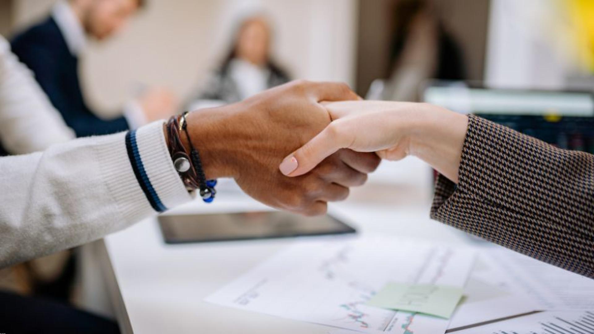 Close-up of two individuals shaking hands in a corporate setting
